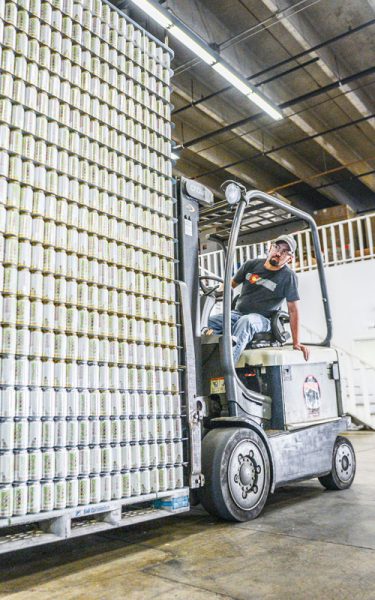 Fork lift and driver loading a skid with beer cans